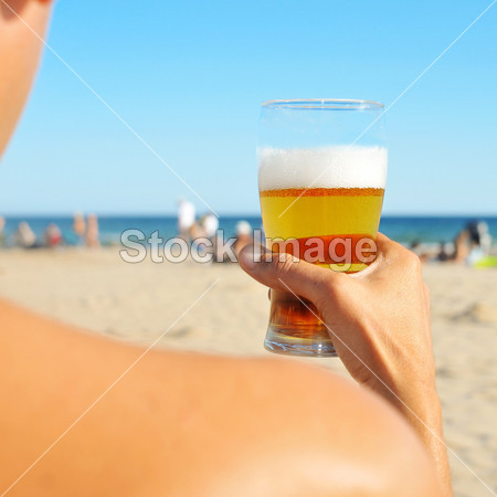 ng man having a refreshing beer on the beach图