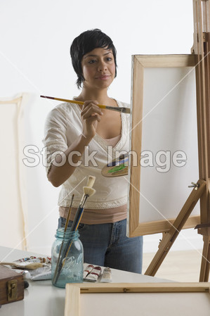西班牙裔美国人的女人在画架上绘画图片素材(
