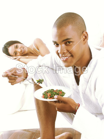 西班牙裔美国人的年轻夫妇享受和在床上吃意大