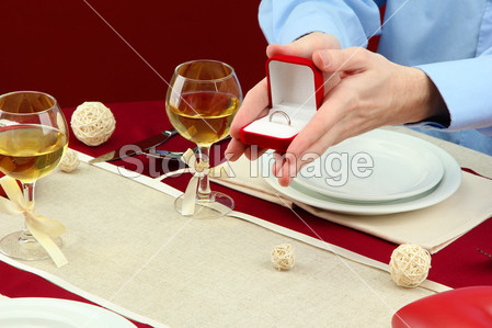 一个人提出,并举行了订婚戒指的餐厅桌子图片