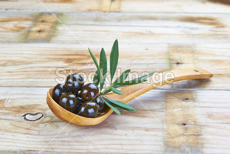 Wooden spoon with olives on the table图片素材