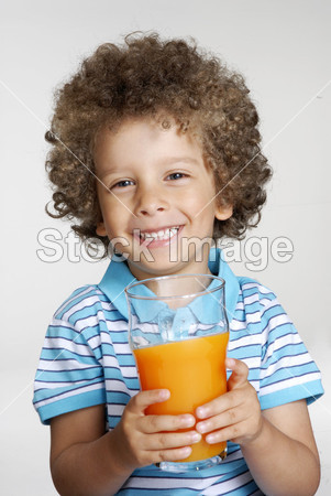 快乐小小的孩子持有橘汁玻璃、 喝橙汁图片素