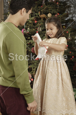 西班牙裔美国人的父亲看着女儿打开圣诞礼物图