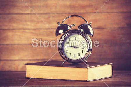 Alarm clock and book. Photo in old color image