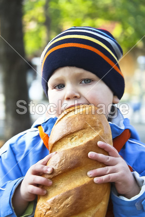 孩子在公园里的秋天散步期间吃面包图片素材(