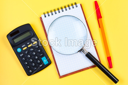 电子计算器、 记事本和黄色的放大镜图片素材