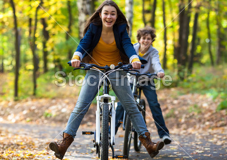 城市自行车-骑自行车在城市公园中的青少年