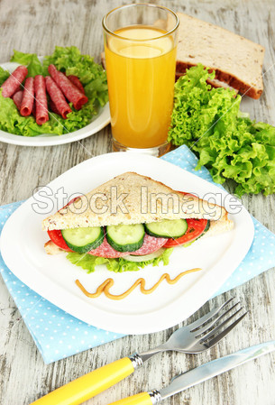 作文与果汁和美味三明治与萨拉米香肠和蔬菜上