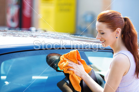 ry wiping her black car on summer sunny day图