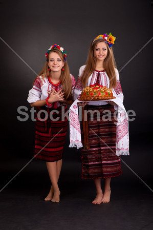 年轻妇女在乌克兰的衣服,与花环和圆面包上图
