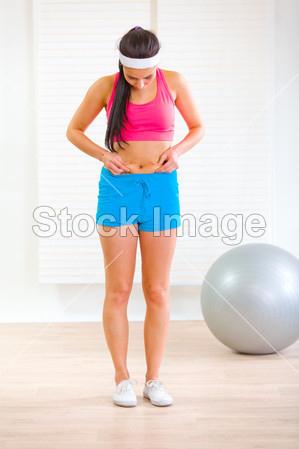 苗条的年轻<em>女子</em>,<em>检查</em>她的<em>身体</em>脂肪的全长肖像