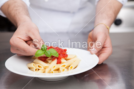 Chef Adding Fresh Basil to Plate of Pasta图片