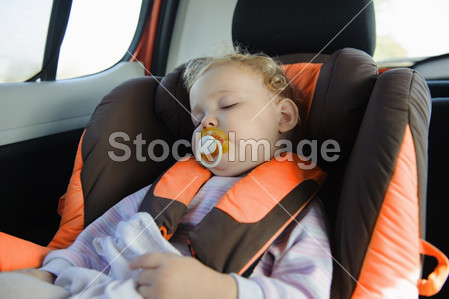 蹒跚学步的姑娘在睡觉的婴儿汽车座椅图片素材