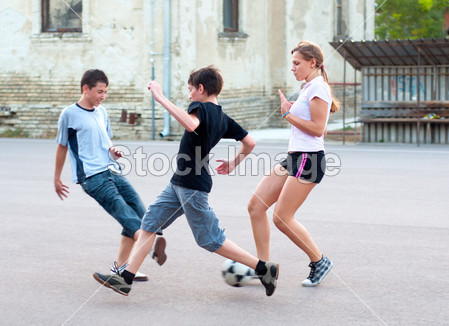 十几岁的男孩和女孩在操场上踢足球图片素材(