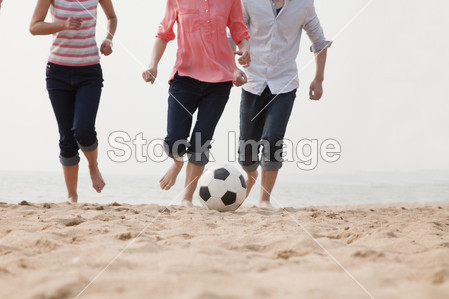 Young Friends Playing Soccer on the Beach图片