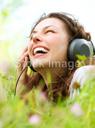 美丽的年轻女子带耳机户外活动。欣赏音乐图片