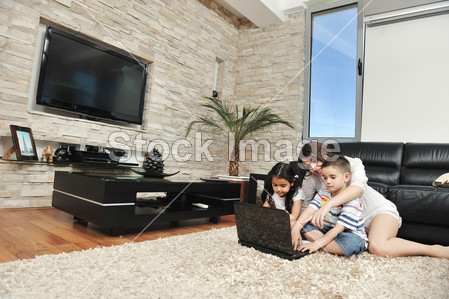 快乐年轻的家庭有乐趣和手提电脑在家里工作