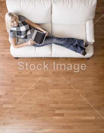 女人在沙发上用的笔记本电脑的顶视图(图片编