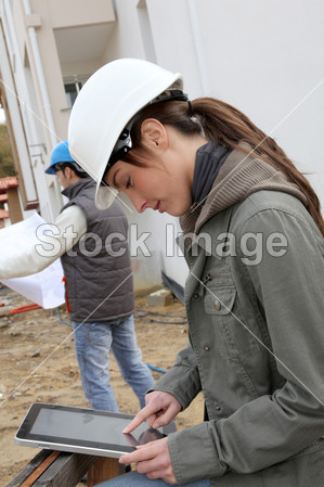 与白色安全头盔站在建筑工地上的女工程师(图