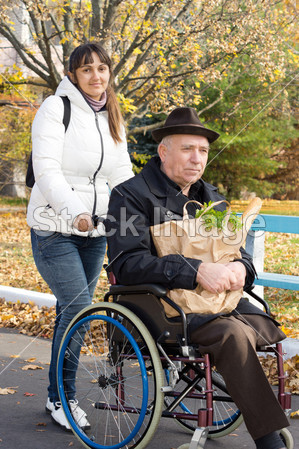 Smiling woman helping her disabled father图片