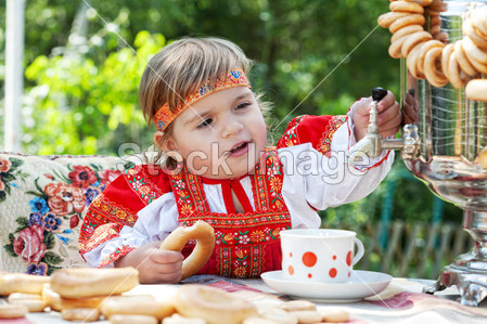 俄罗斯民族服装的女孩从茶炊喝茶图片素材(图