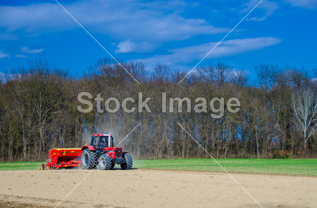 Red tractor on an acre in spring图片素材(图片编